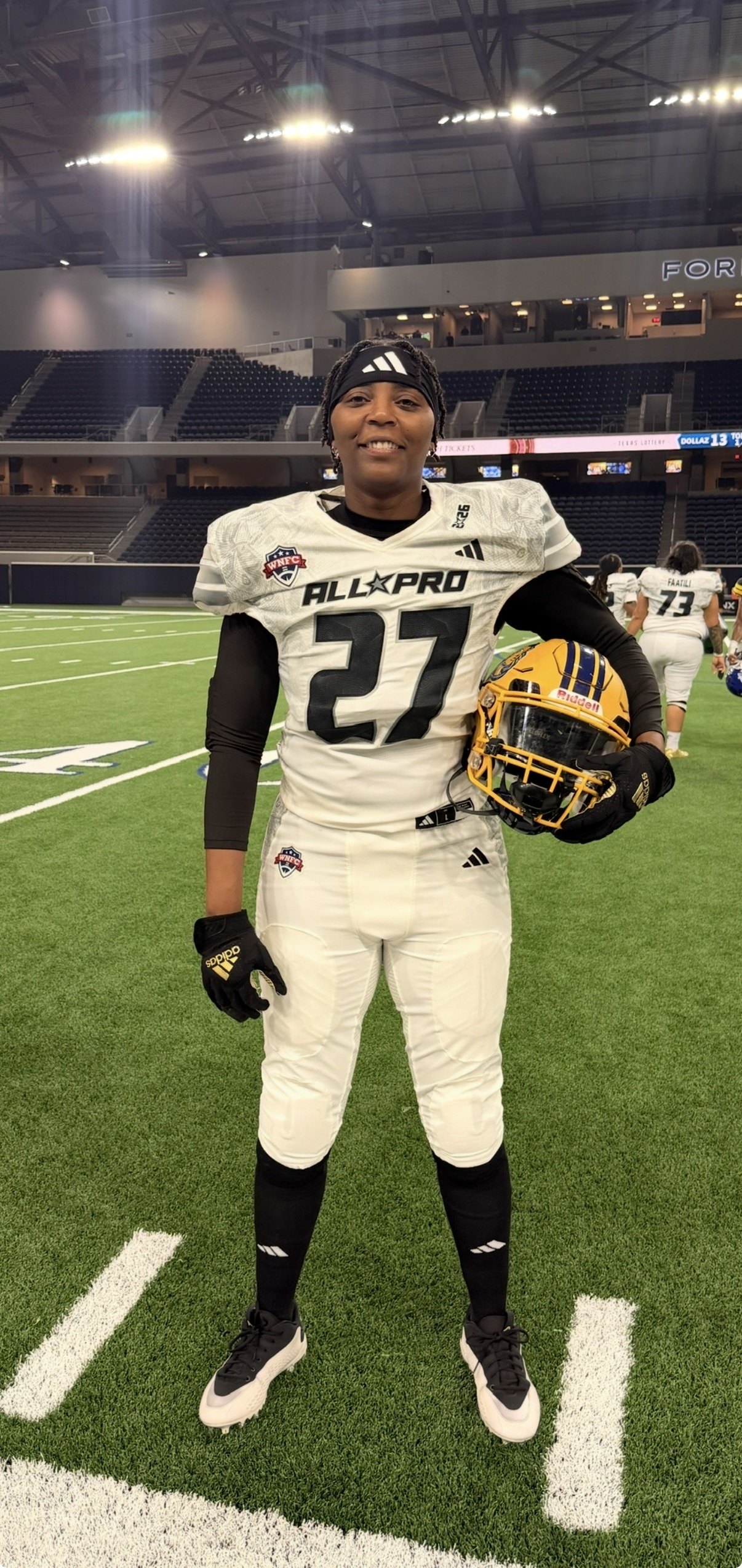 Bennett on the field in the white WNFC All Pro jersey, holding her Golden State Storm helmet