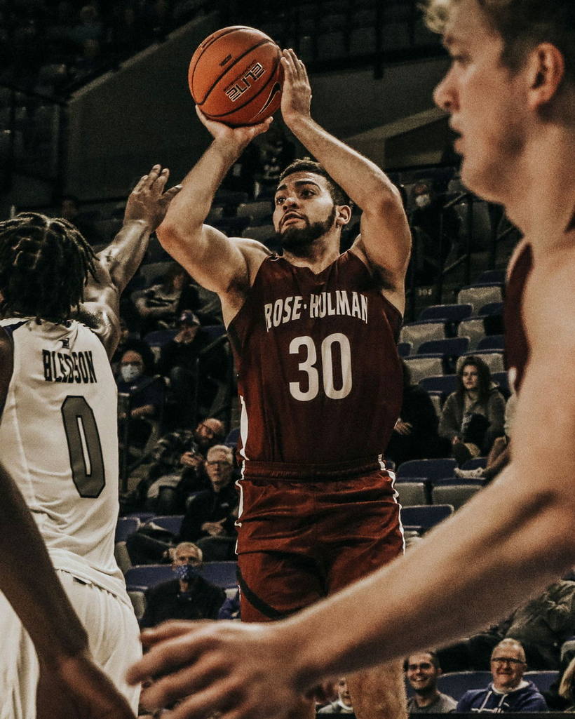 A basketball player rising into a contested shot